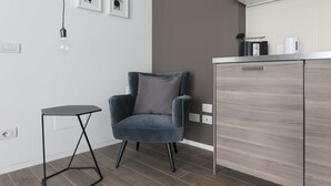 A modern kitchen with a grey cabinet, a small black table, and a grey armchair.