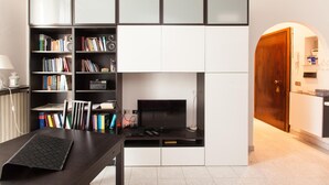 Un salon moderne doté d’un meuble de rangement intégré pour les appareils multimédias, d’un téléviseur à écran plat et d’une bibliothèque remplie de livres et d’objets décoratifs.
