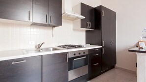 Une cuisine moderne avec des meubles de rangement aux couleurs sombres, un évier en acier inoxydable, une cuisinière à gaz et un four.