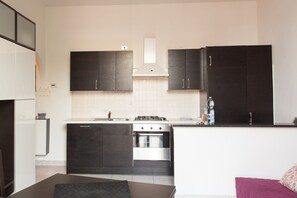 A compact kitchen with dark cabinets, a stove, and a sink.