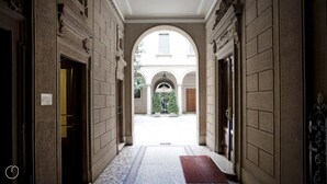 A corridor with a tiled floor leading to a courtyard with a fountain and greenery. - Italianway Easy - Vincenzo Monti 32 (Milan)