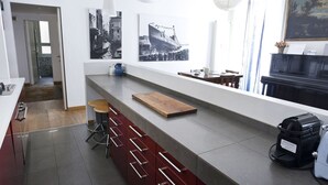 A modern kitchen with a long countertop, bar stools, and a coffee machine. - Italianway Easy - Vincenzo Monti 32 (Milan)
