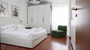 A hotel room with a bed, a green armchair, a wardrobe, and artwork on the wall. - Italianway Comfort - Zanella 10 (Milan)