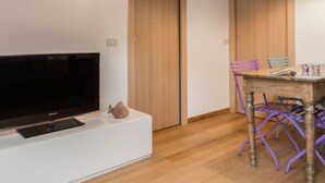 A modern living room with a flat-screen TV, wooden doors, and a dining area with a table and chairs. - Italianway Easy - Savona 108 (Milan)