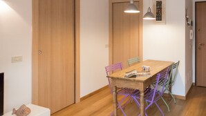 A dining area with a wooden table, colorful chairs, and pendant lighting. - Italianway Easy - Savona 108 (Milan)