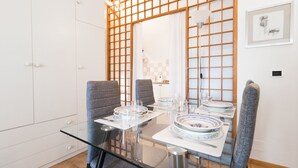A modern dining area with a glass table, grey upholstered chairs, and a traditional Japanese shoji screen in the background. - Washington 91 (Milan)