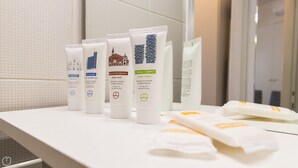 A bathroom counter with various toiletries including shampoo, hair conditioner, body wash, and body cream. - Washington 91 (Milan)