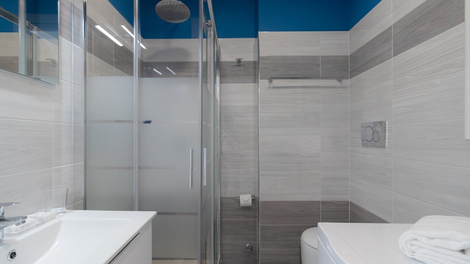 Une salle de bain moderne avec une douche à parois de verre, un lavabo blanc et des toilettes.