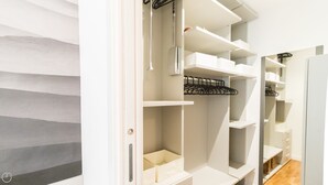 A walk-in closet with multiple shelves and hanging space, organized with white storage boxes and a black hanger rack. - Italianway Easy - Ciro Menotti 18 (Milan)