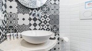 A bathroom with a large, round sink, a mirror, and patterned tiles. - Italianway Easy - Pasubio 12 (Novate Milanese)