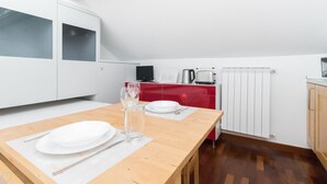 A modern kitchen with white cabinets, a wooden table set with plates, cutlery, and a glass of water. - Ripa Ticinese 43 (Milan)