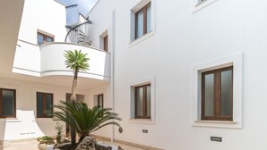 A modern building with a white exterior, multiple windows, and a central balcony with a palm tree. - Ag-e431-bonf8f1 Ottoventi Apartments Tramontana (Lampedusa)