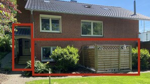 Een huis met twee verdiepingen, een bakstenen gevel, een pannendak en een omheinde achtertuin.