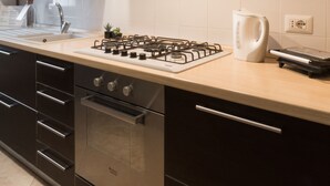 Una cocina moderna con estufa a gas, horno, gabinetes de acero inoxidable y salpicadero de azulejos.