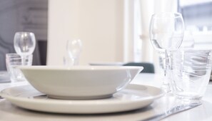A dining table with a white bowl on a plate, a glass of water, and a glass of wine.