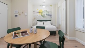 A hotel room with a bed, a round table with chairs, a coffee table with a magazine, and a painting on the wall. - Italianway Easy - Garibaldi 104 A (Milan)
