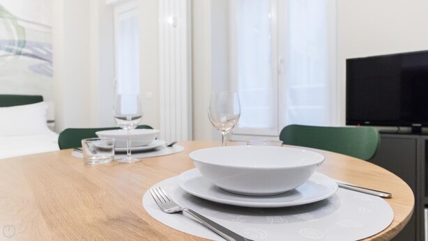 A dining table with a white bowl, two wine glasses, and a fork on a placemat. - Italianway Easy - Garibaldi 104 A (Milan)