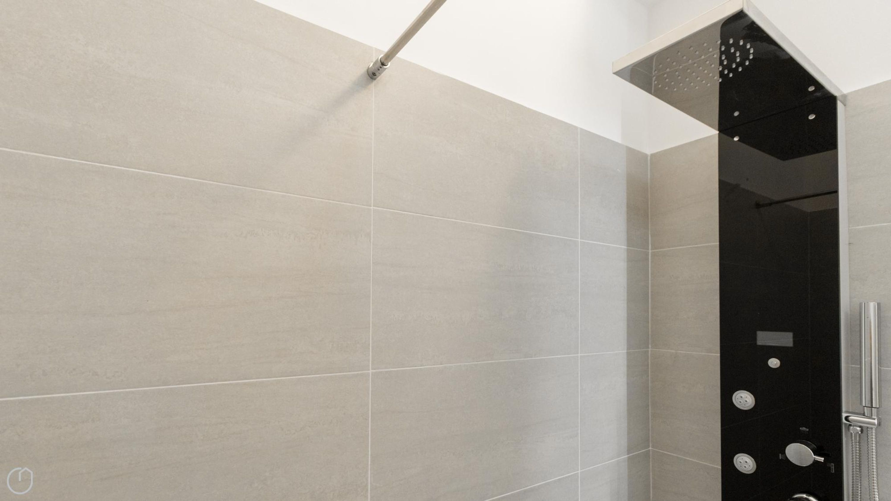 A modern shower with a black panel and a silver faucet.