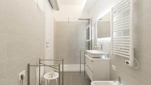 Une salle de bain moderne avec une douche à l’italienne, un lavabo et des toilettes.