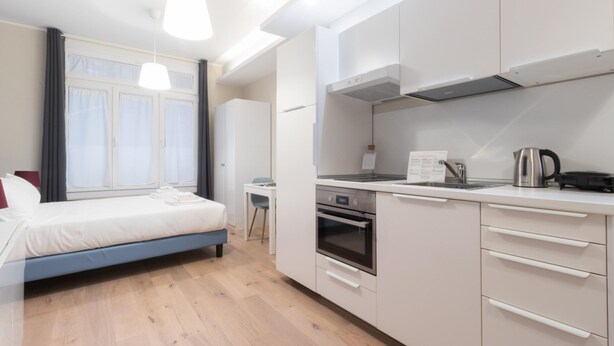 Une chambre d’hôtel moderne comprenant un lit, une kitchenette, un coin repas et une salle de bain.
