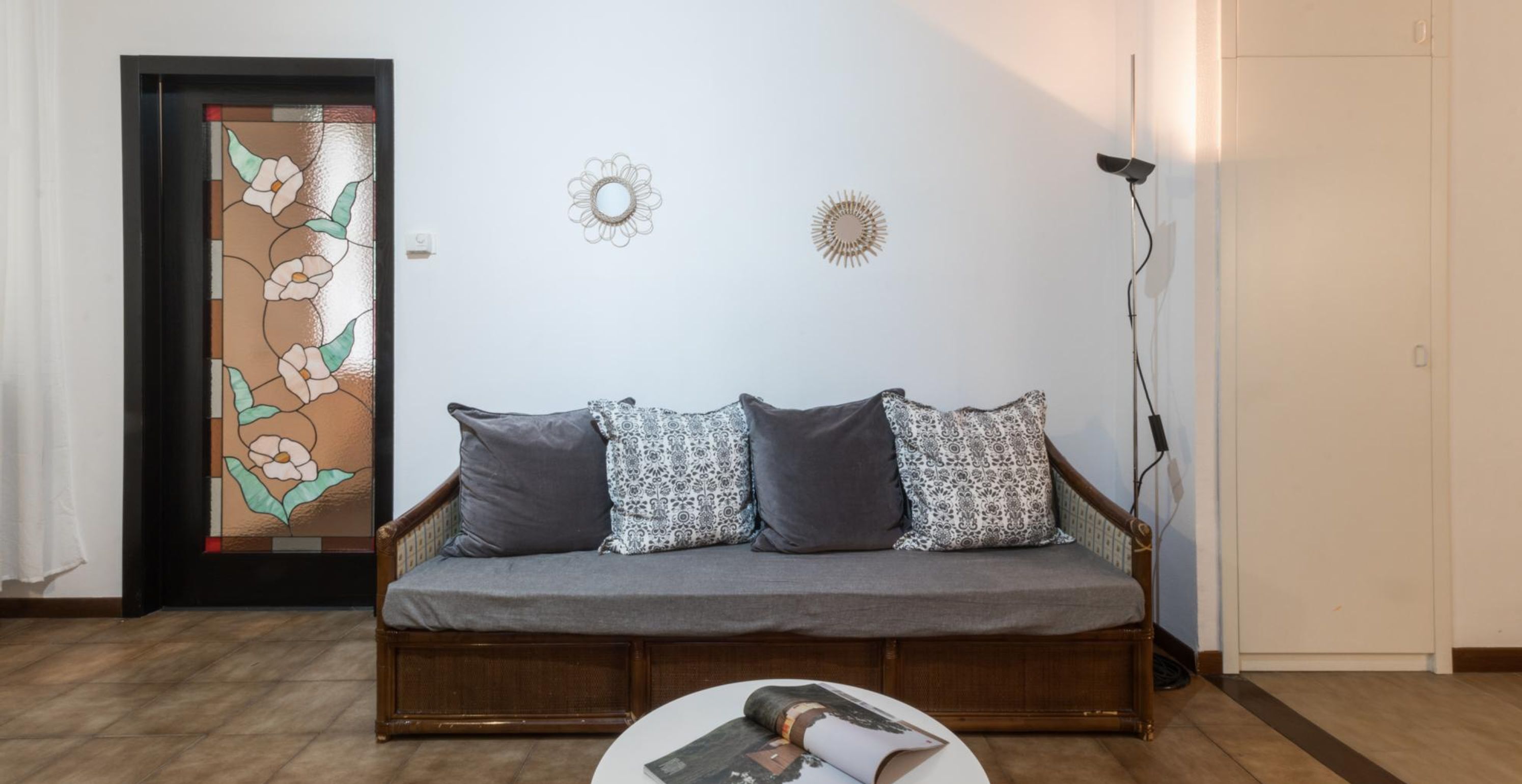 Ein Wohnzimmer mit einer Couch, einem Couchtisch, einer Tür mit Buntglasdekor und Wandverzierungen.
