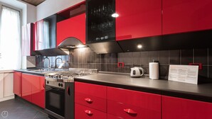 A modern kitchen with red cabinetry, a gas stove, and a kettle on the counter. - Italianway Easy - Massarani 5 (Milan)