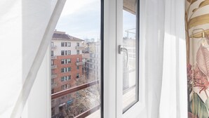 Vista desde una ventana con barandilla metálica, sobre una hilera de edificios con balcones.