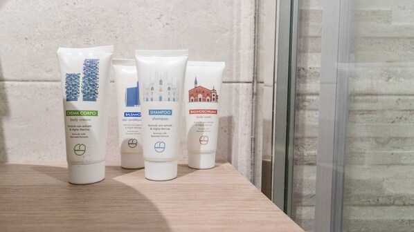 Four skincare products on a wooden shelf against a textured wall.