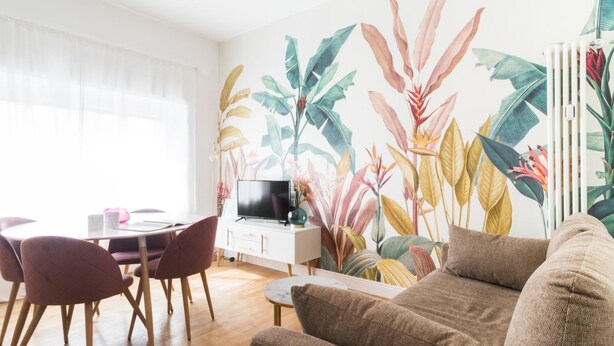 Una sala de estar con comedor, un televisor de pantalla plana y una amplia pared cubierta de plantas tropicales.