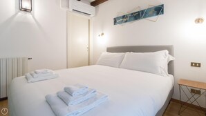 A neatly made bed with white linens and folded towels, a bedside table, and a wall-mounted artwork. - Italianway Easy - Tadino 13 (Milan)