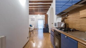 A kitchen with wooden cabinets, a stove, and a microwave. - Italianway Easy - Tadino 13 (Milan)