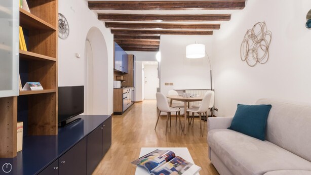 A modern living room with a flat-screen TV, a sofa, a dining table with chairs, and a kitchen area in the background. - Italianway Easy - Tadino 13 (Milan)