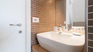 A bathroom with a large white sink, a mirror, and a tiled wall. - Italianway Easy - Ampere 103 (Milan)