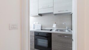 A modern kitchen with a built-in oven, a stainless steel sink, and light-colored cabinetry. - Italianway Easy - Ampere 103 (Milan)