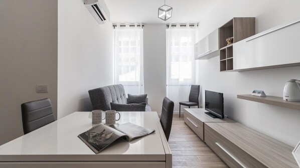 Un espacio de oficina moderno y minimalista, con un escritorio grande, dos sillas, un televisor y estanterías empotradas.