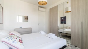 A modern hotel room with a large bed, a bedside table, a mirror, and a wardrobe. - Italianway Comfort - Ripa Ticinese 103 (Milan)
