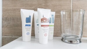 Trois flacons de produits de toilette et un verre transparent sur une surface blanche.