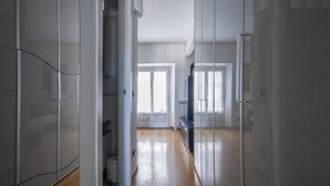 Un estrecho pasillo con suelo de madera que conduce a una puerta con un ventanal.