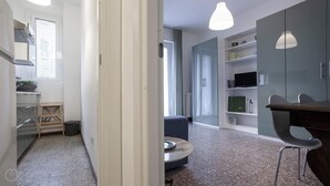 Una cocina moderna con horno empotrado, una zona de comedor con una mesa redonda y sillas, y un mueble grande con estantes.