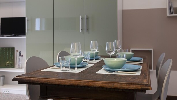 Una mesa de comedor con platos y vasos azules, rodeada de sillas.