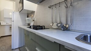 Una cocina moderna con un lavamanos de acero inoxidable, una estufa a gas y utensilios de cocina colgantes.