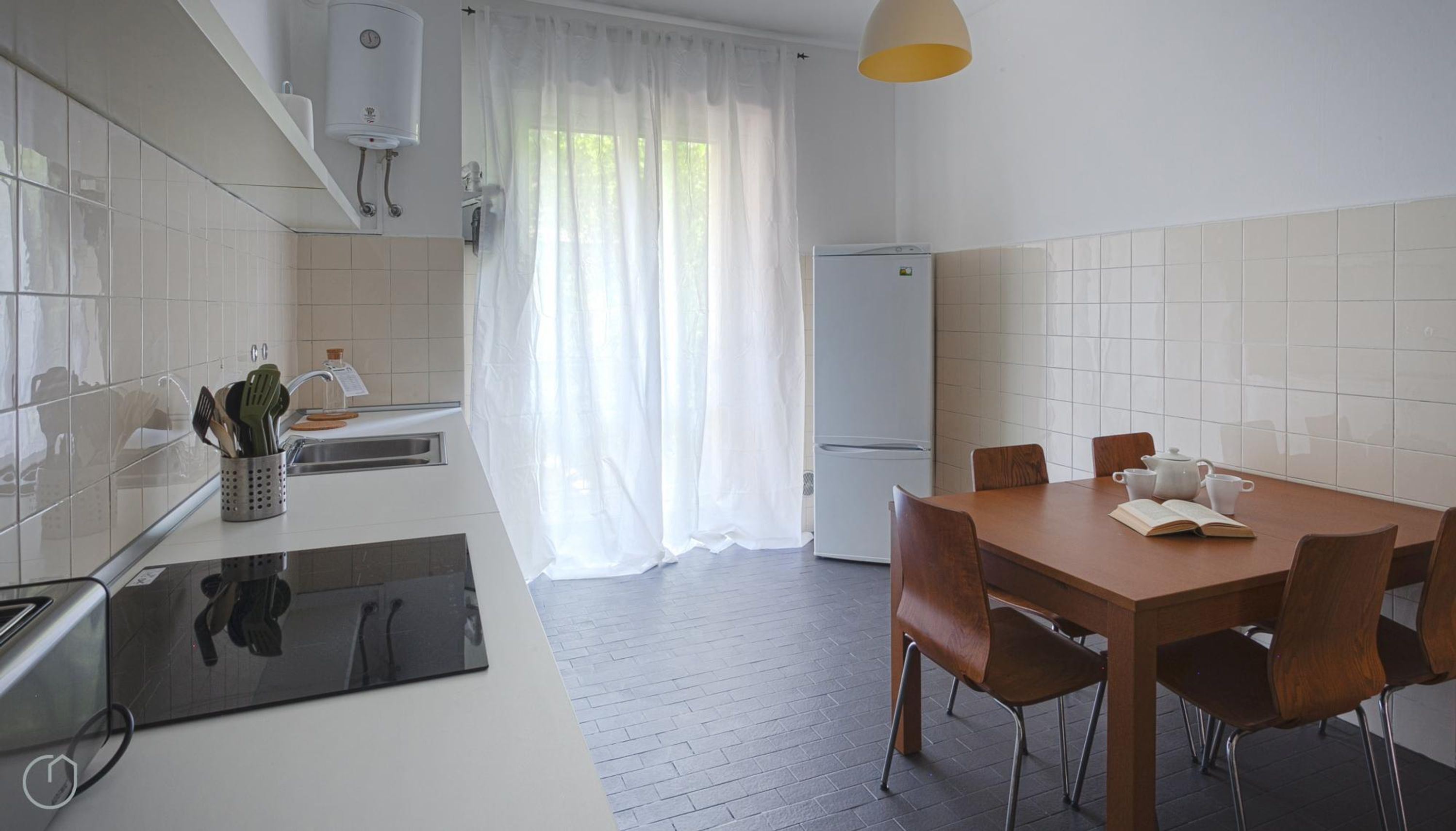 A modern kitchen with a dining area, featuring a built-in stove, a sink, and a refrigerator.