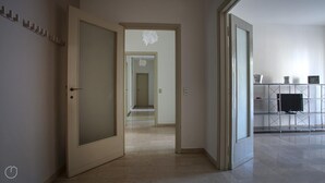 Un pasillo con una puerta que da a una habitación, una escalera y un mueble con un televisor.