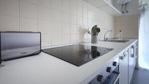 Una cocina moderna con una hornilla de inducción negra elegante, armarios blancos y un lavamanos de acero inoxidable.