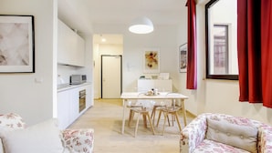 A modern kitchen with a microwave, oven, and dining area with a table and chairs. - Bergonzoli Place (Milan)