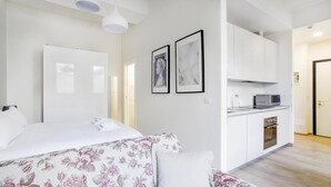 A modern bedroom with a bed, a sofa, and a kitchenette with a microwave and oven. - Bergonzoli Place (Milan)