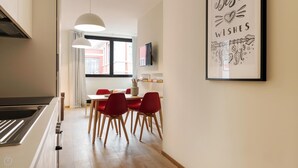 Cocina moderna con comedor, que incluye una isla de cocina, sillas rojas y una lámpara colgante.