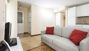 Un salon moderne avec un canapé gris, des coussins rouges et un téléviseur à écran plat.