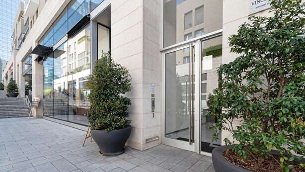 Een modern gebouw met een glazen gevel, een grote potplant en een bord met de tekst 'VINCI MEDAGLIA'.