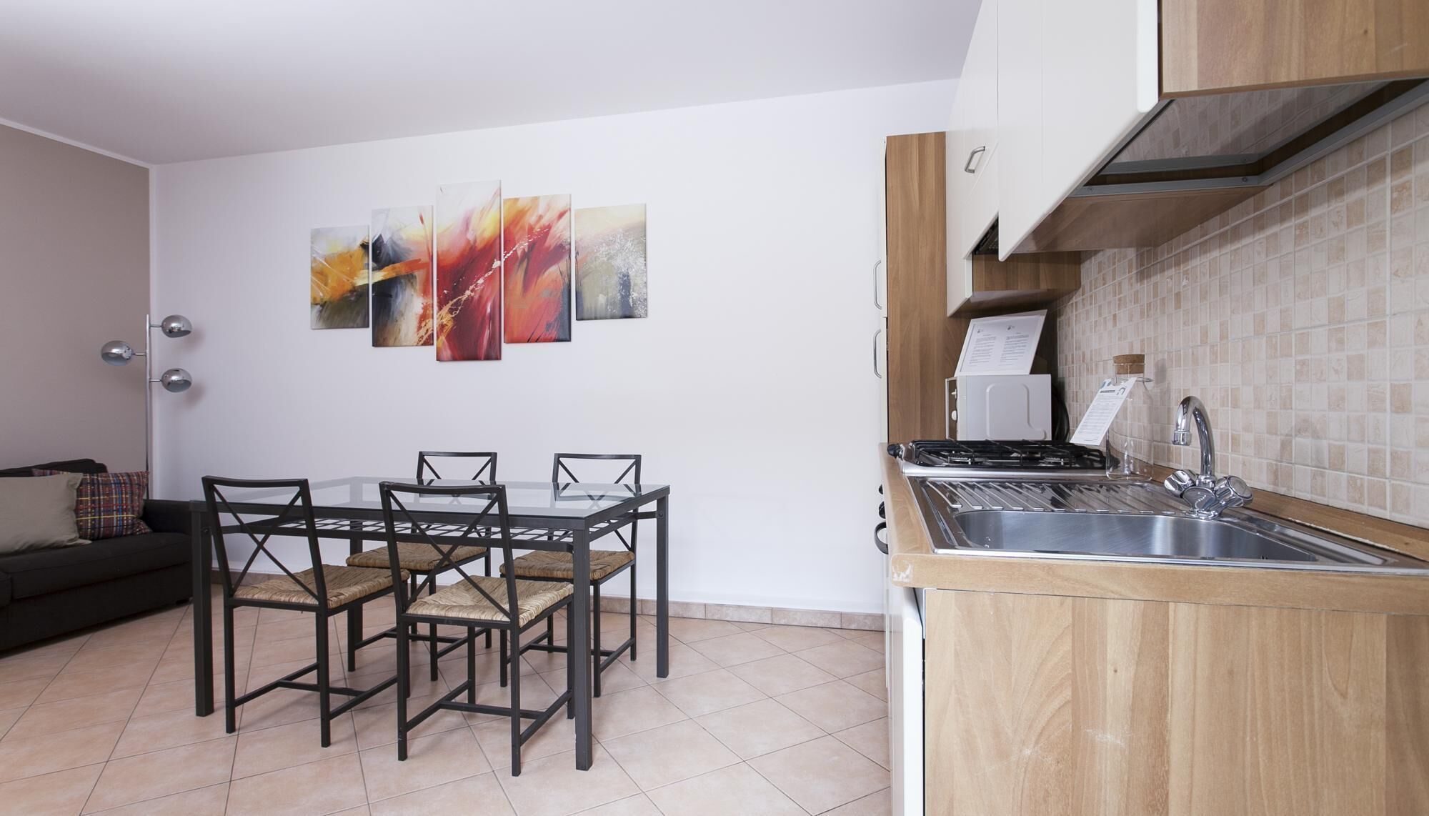 Cozinha compacta com área de jantar, com fogão moderno, pia e mesa com cadeiras.